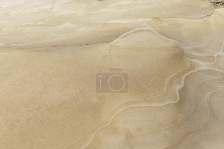 Close-up of a smooth sandstone surface featuring gentle erosion patterns and subtle textures. Ideal for backgrounds, nature themes, and geological studies.