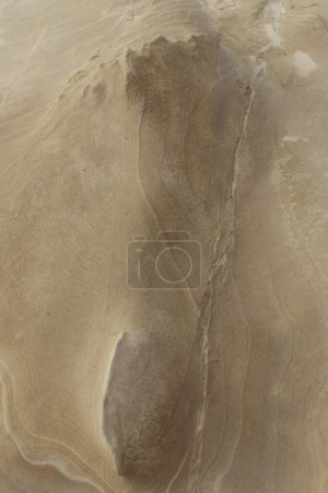 Close-up of a smooth sandstone surface featuring natural erosion patterns and subtle textures. Ideal for backgrounds, nature themes, and geological studies.