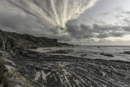 Ciel mouillé avec des formations de nuages spectaculaires au-dessus de Carriagem Beach, Portugal. Le littoral accidenté et les formations rocheuses créent une scène frappante et atmosphérique au crépuscule.