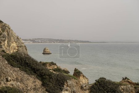 Vue panoramique sur les falaises rocheuses et les piles de mer à Camilo Beach au Portugal. Le littoral accidenté présente des formations rocheuses spectaculaires et une plage de sable fin.