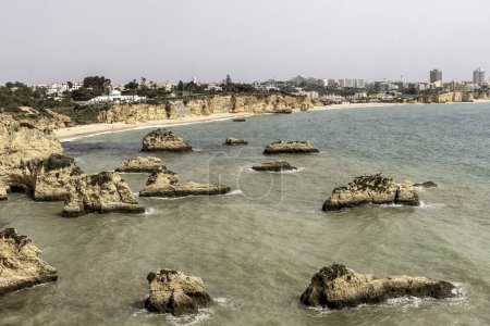Stunning view of coastal rock formations and sea arches in Portimao, Portugal. The rugged cliffs and scattered sea stacks create a dramatic and picturesque seascape.