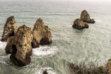 Stunning view of coastal rock formations and sea arches in Portimao, Portugal. The rugged cliffs and scattered sea stacks create a dramatic and picturesque seascape.