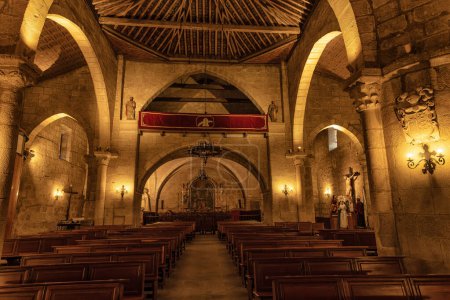 Das ruhige Innere der Basilika Santa Eulalia in Merida, Spanien, mit steinernen Bögen, hölzernen Bänken und einem schön beleuchteten Altar.