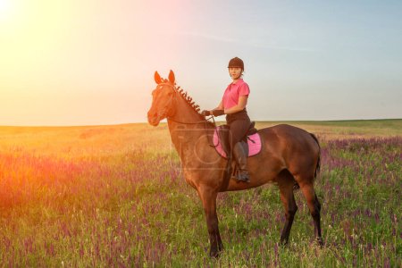 Téléchargez les photos : Femme cheval jockey en uniforme à cheval à l'extérieur. Coucher de soleil. Promenade à cheval. La concurrence. hobby - en image libre de droit
