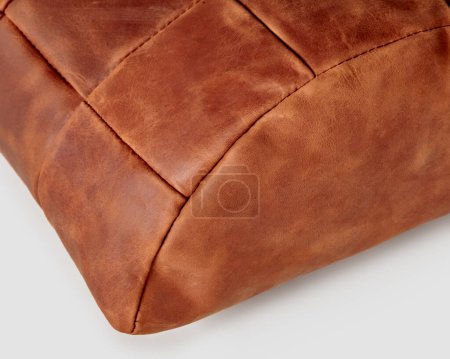 Foto de Closeup of half-cylindrical footrest cushion handmade from patches of genuine copper-colored leather. Stylish soft interior accessory, ideal for comfortable work at table - Imagen libre de derechos
