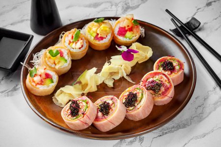 Photo for Two types of rolls wrapped in mamenori with tuna, crab meat, avocado and black tobiko served on plate with pickled ginger, shredded daikon and soy sauce. Japanese food. Sushi bar menu concept - Royalty Free Image