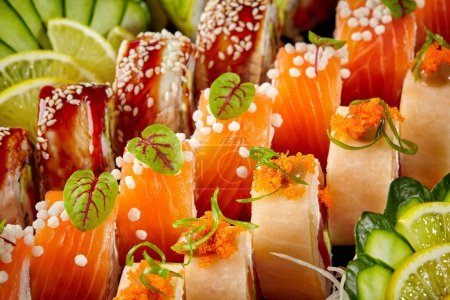 Nahaufnahme eines bunten Sushi-Sortiments mit Lachs, Aal, Tobiko, Sesam, knusprigen, luftigen Reisbällchen, garniert mit Gurkenscheiben, Zitrusfrüchten und Gemüse. Japanische Küche