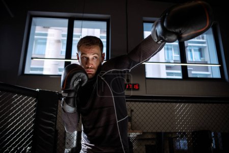 Photo for Concentrated young adult bearded boxer honing punching skills while shadowboxing to build speed and muscle memory of body in modern boxing gym - Royalty Free Image