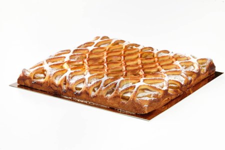 Delicious apple galette with crispy baked lattice top, filled with delicate custard, sprinkled with fine layer of powdered sugar, presented on white background