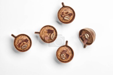 Elegante Schokoladenbonbons mit Kaffeefüllung, die Miniatur-Kaffeetassen ähneln, auf weißem Hintergrund