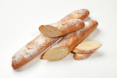 Closeup of freshly baked whole and sliced wheat baguettes isolated on white background. Main staple. Artisanal breadmaking concept