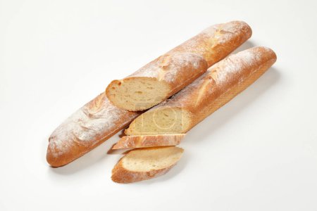 Zwei ganze und in Scheiben geschnittene frische französische Baguettes mit goldener Kruste und luftiger Konsistenz, isoliert auf weißem Hintergrund. Konzept für traditionelle Backwaren