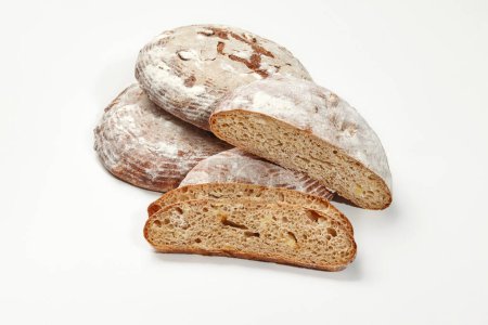 Close-up of whole and sliced freshly baked artisan sourdough round bread with crispy crust dusted with flour and airy soft texture, isolated on white background