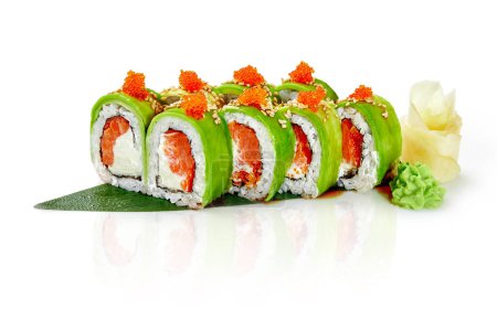 Köstliche grüne Sushi-Rolle mit Lachs, Frischkäse und Tobiko in Avocadoscheiben gewickelt und mit Unagi-Sauce beträufelt, traditionell serviert mit Gari und Wasabi auf Bambusblatt, isoliert auf weißem Hintergrund