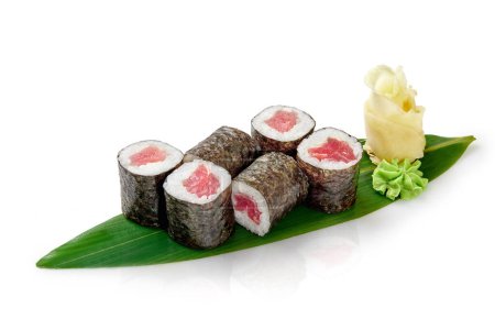 Deliciosos rollos frescos de tekka maki rellenos de filete de atún y arroz envueltos en nori, servidos tradicionalmente con jengibre en escabeche y wasabi sobre hoja de bambú, aislados sobre fondo blanco. Menú barra de sushi