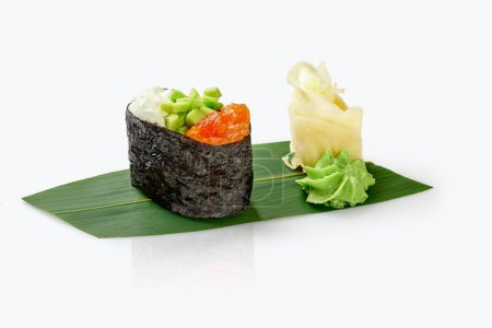 Gunkan maki sushi with salmon topping, diced avocado and mayo, served with wasabi and ginger on bamboo leaf isolated on white. Traditional Japanese cuisine