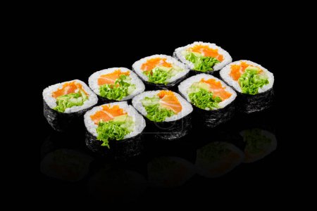 Coloridos rollos de futomaki con salmón fresco, tobiko, aguacate, pepino y lechuga presentados sobre fondo negro. Snack japonés popular