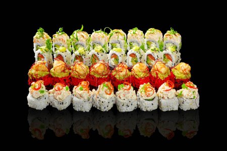Enticing set of sushi rolls with various fillings and toppings garnished with vegetable shavings, togarashi threads and spicy sauce arranged on black background. Japanese cuisine concept