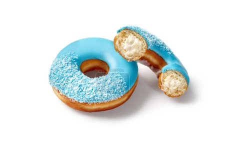 Deliciosas rosquillas suaves dulces con relleno cremoso y glaseado azul colorido espolvoreado con copos de coco, presentado sobre fondo blanco. Sabores brillantes de productos de confitería populares