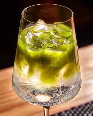 Primer plano del cóctel tónico matcha refrigerado con un tono verde vibrante y una textura espumosa en un elegante vidrio de tallo