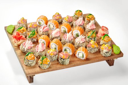 Delicious set of crispy tempura rolls with various toppings and salmon Philadelphia rolls served on wooden tray with spicy wasabi and pickled ginger. Japanese cuisine