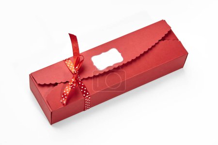 Designer rote Schachtel mit gebogenen Kanten und Branding-Etikett mit charmanten Tupfen-Schleife für Pralinen und Süßigkeiten gebunden, bereit, als durchdachte Gourmet-Geschenk für besondere Anlässe gegeben werden