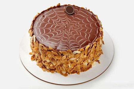 Téléchargez les photos : Gâteau Esterhazy classique avec un motif de glaçage au chocolat lisse et complexe sur le dessus et un revêtement croquant en flocons d'amande sur les côtés, sur fond blanc. Artisanat de confiserie - en image libre de droit