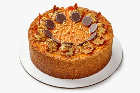 Tender aromatic pumpkin cheesecake with crunchy shortcrust nut base and sweet caramel decorated with delicate cream and chocolate on white background. Harmony of flavors reminiscent autumn