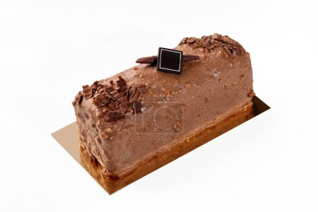 Köstliche handwerkliche Laibchen mit Milchschokolade und Nussglasur überzogen, dekoriert mit dunkler Schokolade Branding Plakette auf goldenem Karton, isoliert auf weiß. Konzept für süßes Gebäck