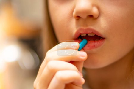 Téléchargez les photos : La fille tenant une pilule près de sa bouche - en image libre de droit
