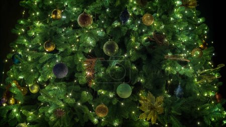 Foto de El árbol de Navidad está decorado con juguetes y guirnaldas. Brillando maravillosamente en la oscuridad. - Imagen libre de derechos