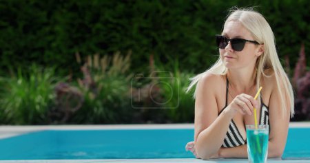 Téléchargez les photos : Portrait d'une femme qui réussit à se détendre dans la piscine avec une boisson fraîche. bonnes vacances et bon repos. - en image libre de droit