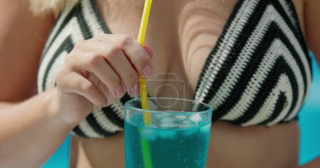 Photo for Woman in bikini shatters ice in a cocktail, close-up. - Royalty Free Image