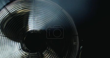 Photo for Fan blades rotate in rays of light and fog. - Royalty Free Image