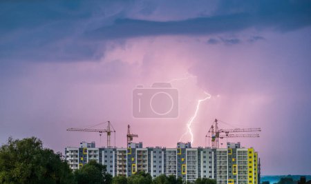 Photo for Lightning cuts the sky, in the foreground the construction of multi-storey residential buildings. - Royalty Free Image