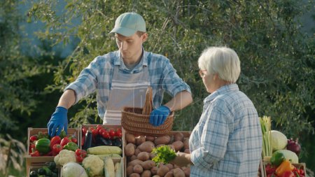 Téléchargez les photos : Femme âgée avec un panier dans la main achète des légumes au marché fermier. - en image libre de droit