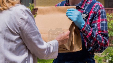 Foto de El mensajero entrega paquetes de productos a la puerta de la casa de los clientes. - Imagen libre de derechos