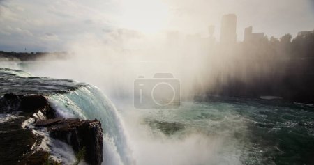 Photo for Spectacular landscape with Niagara Falls. A wall of fog covers the Canadian coast, a boat is floating far below on the river. - Royalty Free Image
