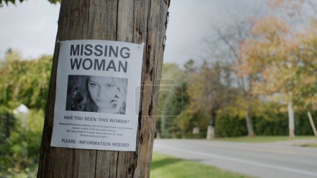 Foto de Un anuncio de una joven desaparecida cuelga en un poste cerca de la carretera. - Imagen libre de derechos
