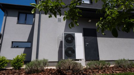 Outdoor unit of a heat pump against the wall of a modern cottage. High quality photo