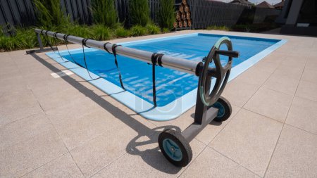Téléchargez les photos : Accueil piscine extérieure couverte de film pour économiser les produits chimiques, l'eau et la préservation de la chaleur. Photo de haute qualité - en image libre de droit