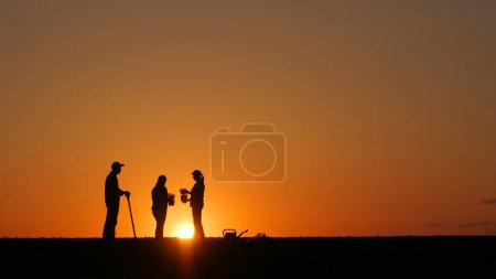 Téléchargez les photos : At sunset, a group of farmers stands ready to plant seedlings in a field - en image libre de droit