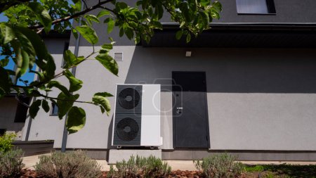 A modern cottages wall accommodates the outdoor unit of a heat pump. High quality photo