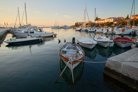 Téléchargez les photos : Marina avec des bateaux amarrés dans la ville croate de Malinska sur l'île de Krk pendant le coucher du soleil - en image libre de droit