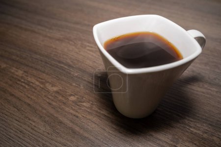 Taza con café negro caliente sobre fondo de madera