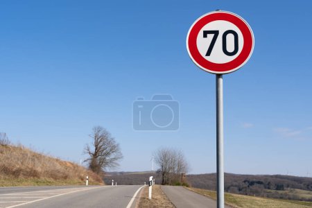 Photo for Speed sign 70 kilometers per hour on a country road with blue sunny sky - Royalty Free Image