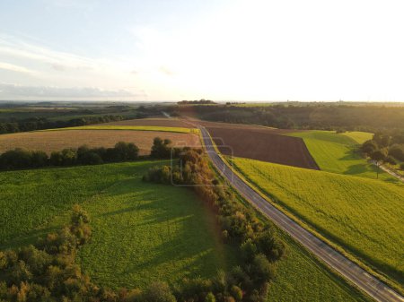 Luftaufnahme einer Landschaft mit Feldern und einer asphaltierten Straße