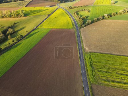 Aerial view of a countryside with farm fields and a long road