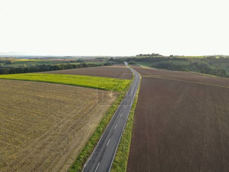 Aerial view of a long road between farm fields in the countryside