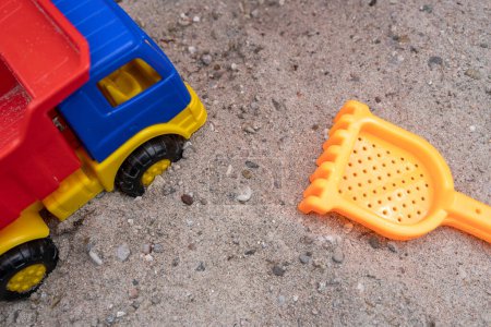 Colorful toy truck and a rake in the sand